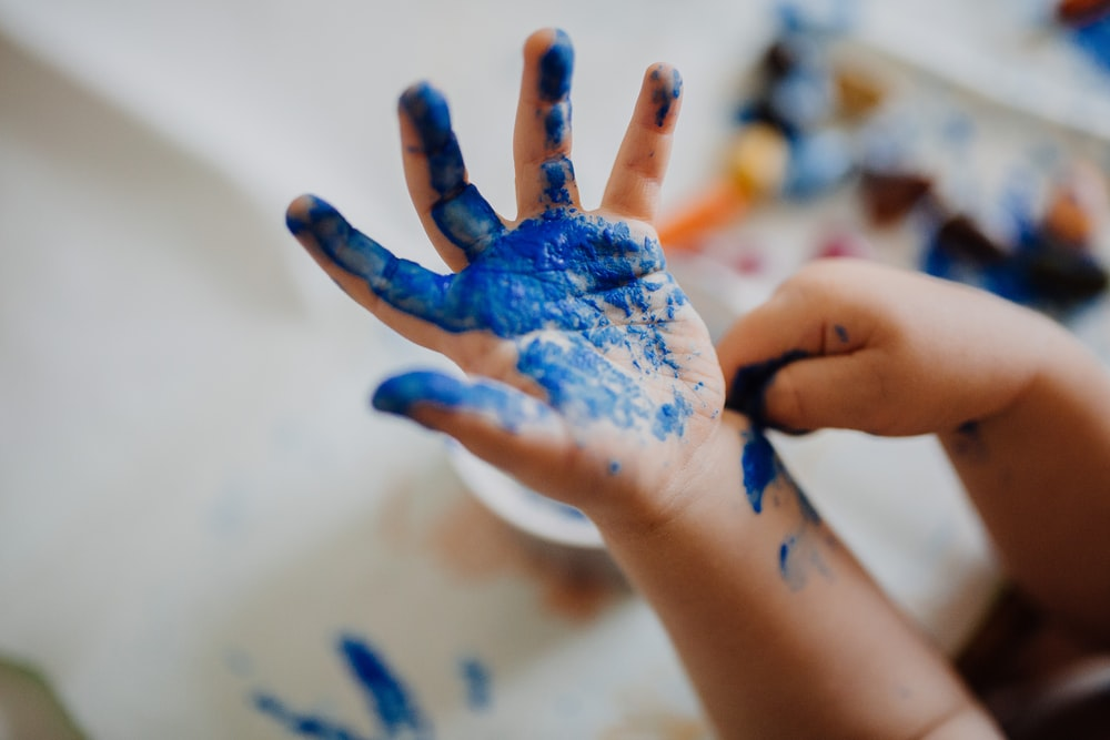 A child’s hand covered in blue paint