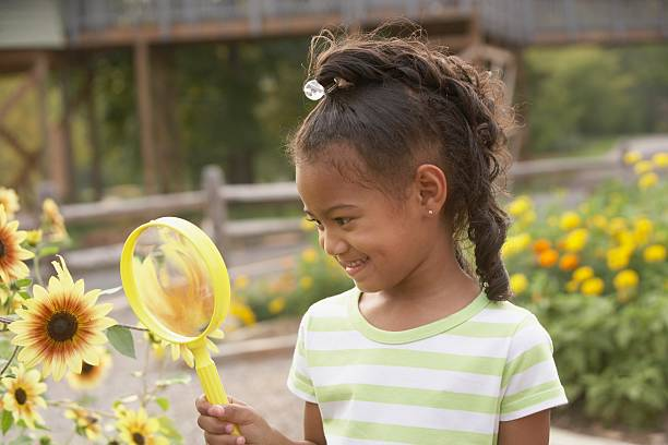 Girl using a magnifying glass to see flowers